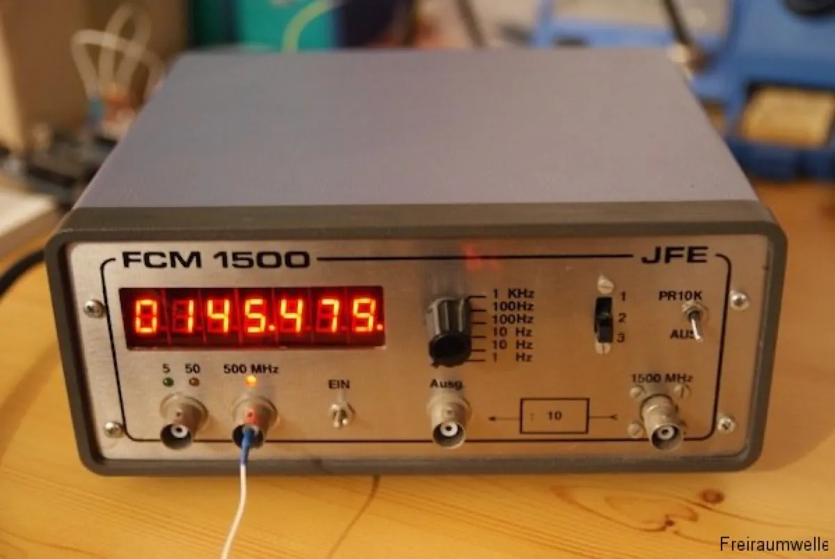 Frontplatte des Frequenzzählers FCM 1500 mit roter Siebensegmentanzeige, die 145,475 MHz zeigt, darunter BNC-Buchsen und Schalter für Torzeit und Messbereich