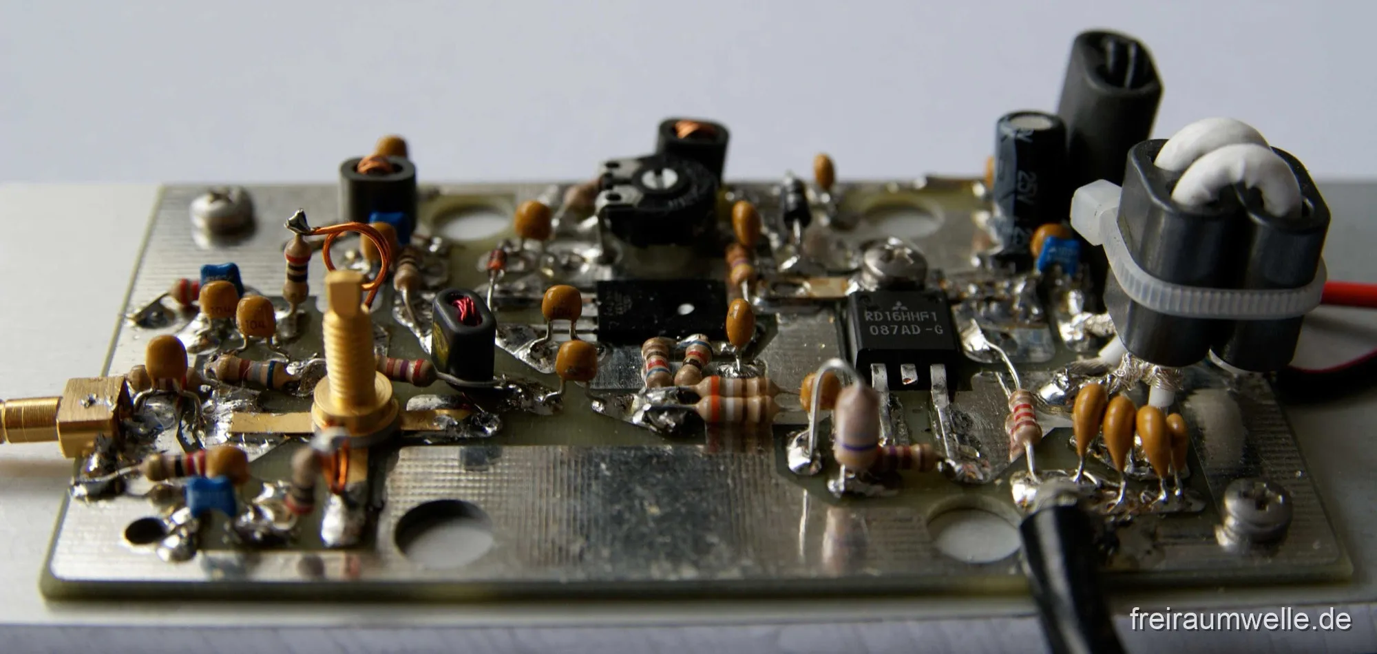 Bestückte Platine der Endstufe, flach von der Seite fotografiert: bedrahtete Widerstände und Kondensatoren, mehrere Ringkerne, ein Trimmpotentiometer und rechts der Leistungstransistor