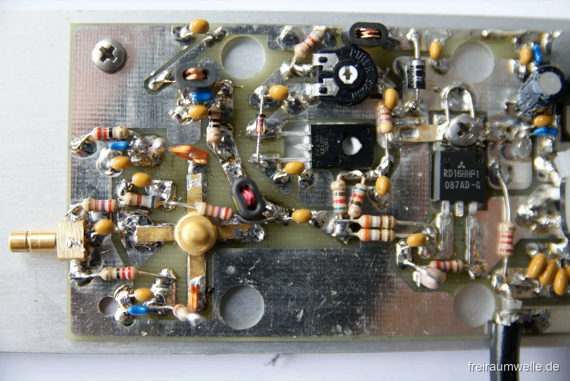 Draufsicht auf den Endstufenbereich der Platine: rechts der Transistor mit Aufdruck RD16HHF1 087AD-G, in der Mitte ein BD137, links eine SMA-Buchse, dazwischen Ringkerne und bedrahtete Bauteile