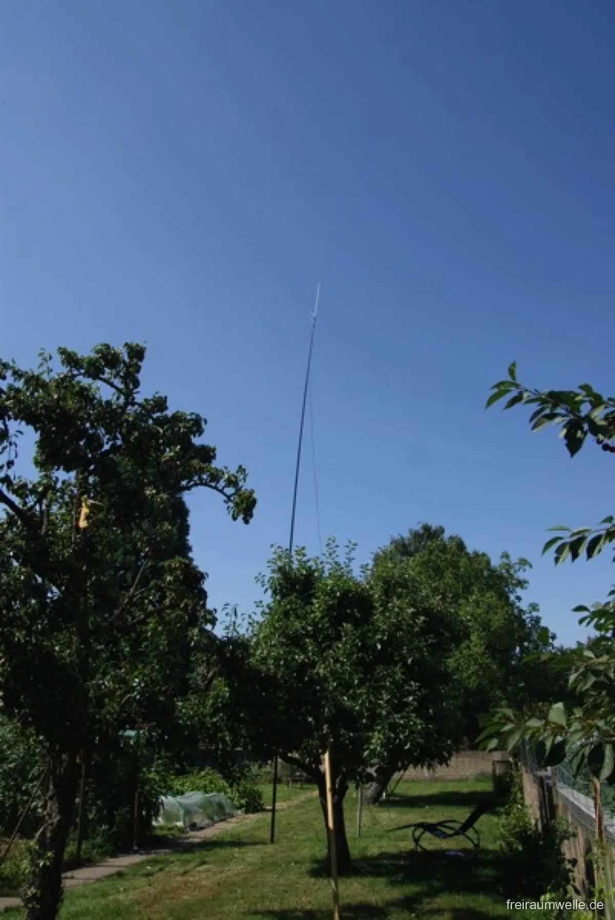 Bequemer Gartenstuhl unter einem Obstbaum, daneben das Handfunkgerät und ein kleiner Tisch als improvisiertes Shack